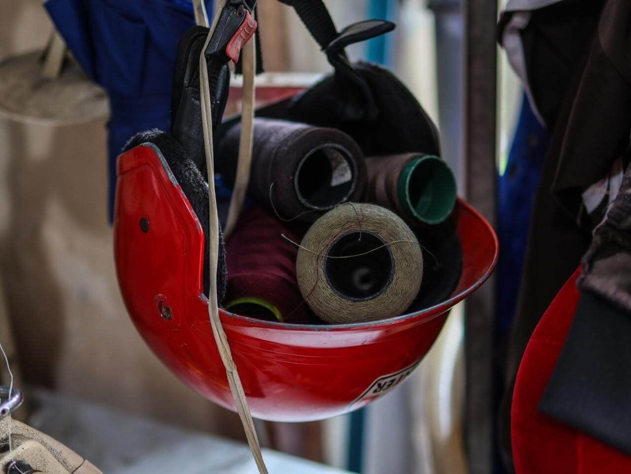 Close up of a red motorcycle helmet used to store sewing thread in a Phnom Penh tailor shop.